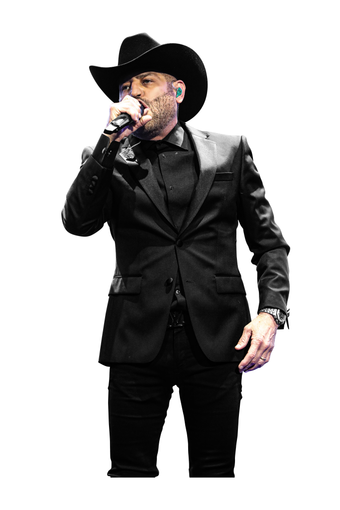 a man in a black suit and cowboy hat singing into a microphone