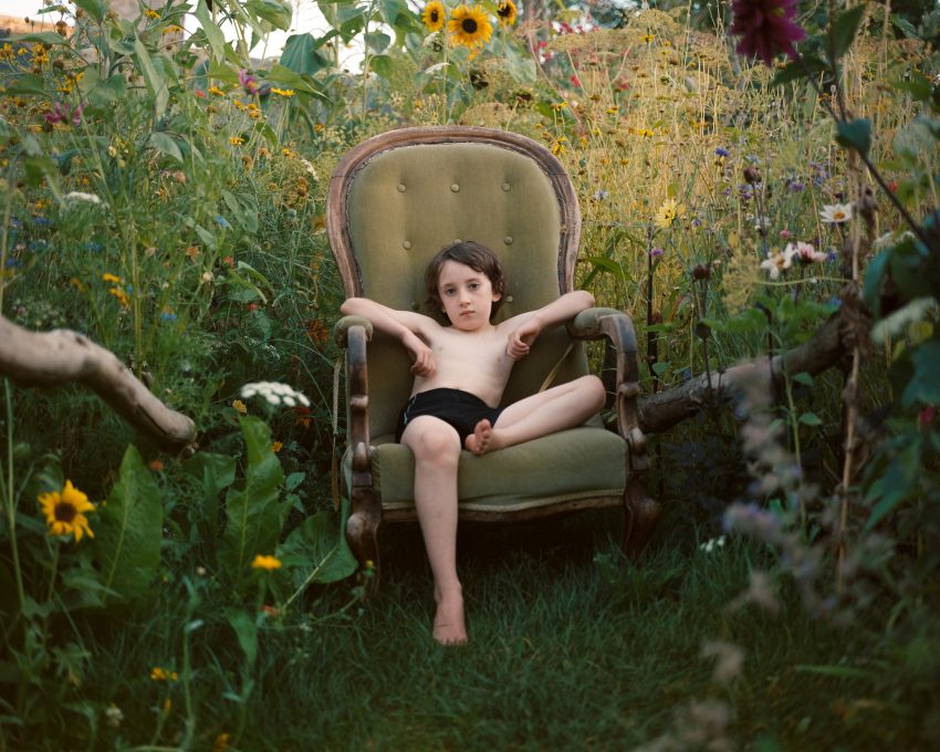 a kid sitting in a chair in a garden